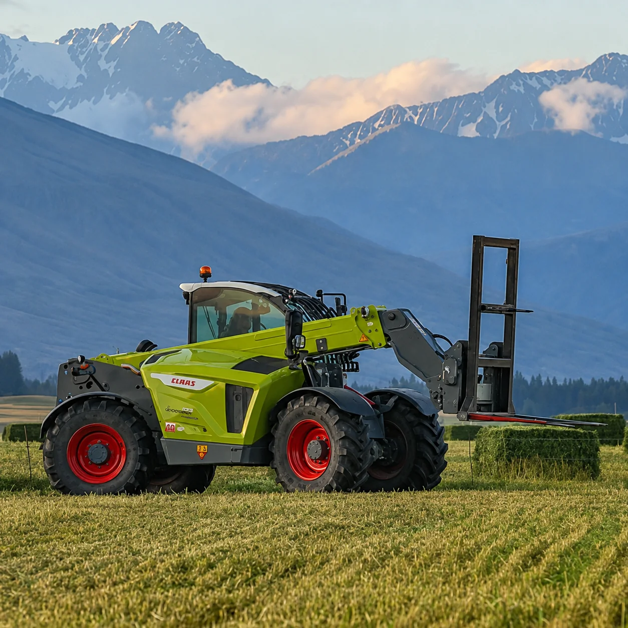 Big JCB loader stacking bales with the Southern Alps behind